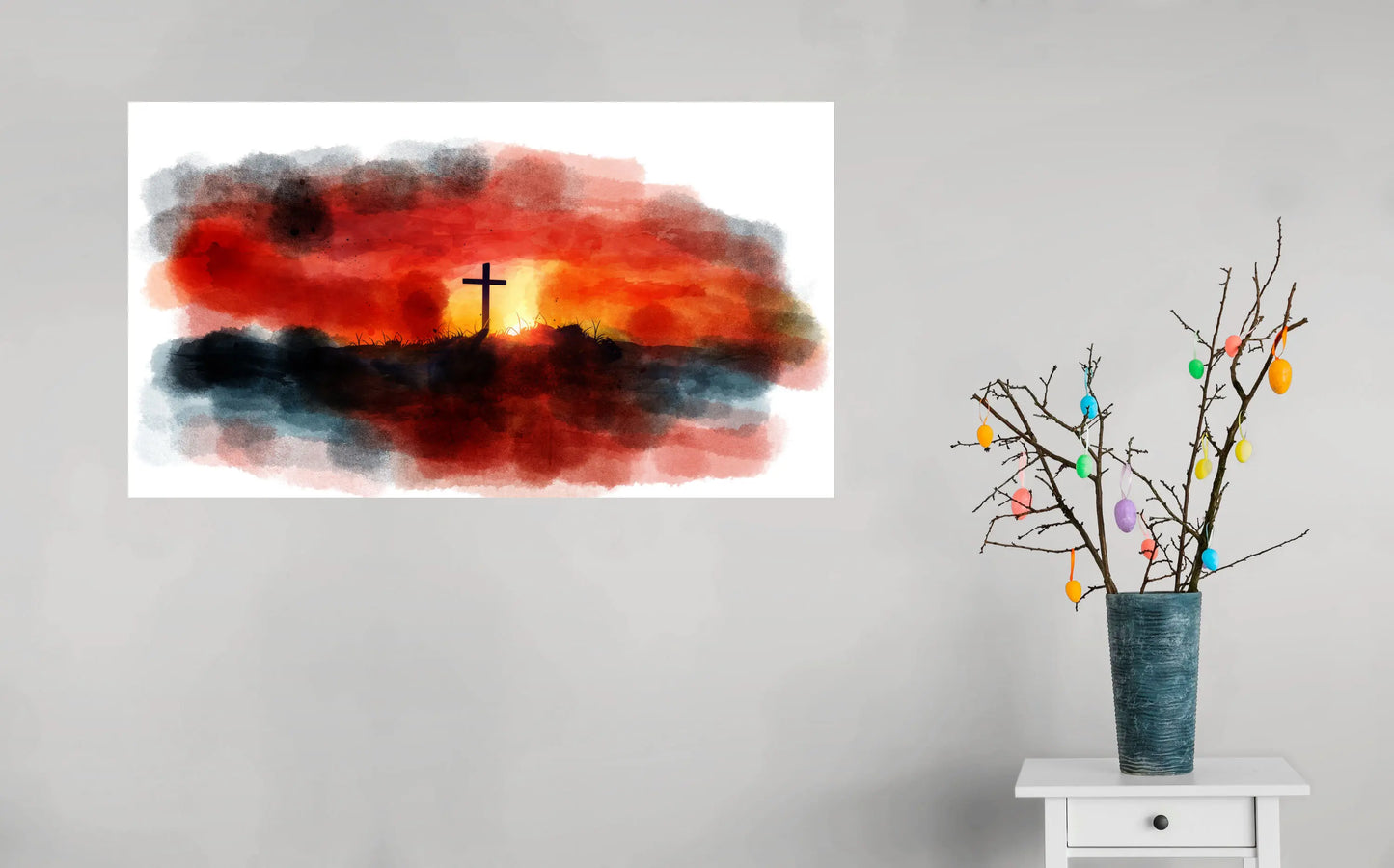 Artistic depiction of a cross against a colorful sunset with a vase of decorative branches on a white surface.