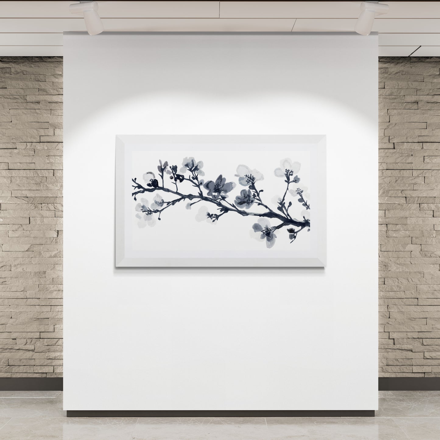 Framed artwork of a floral branch on a white wall with stone walls in the background.