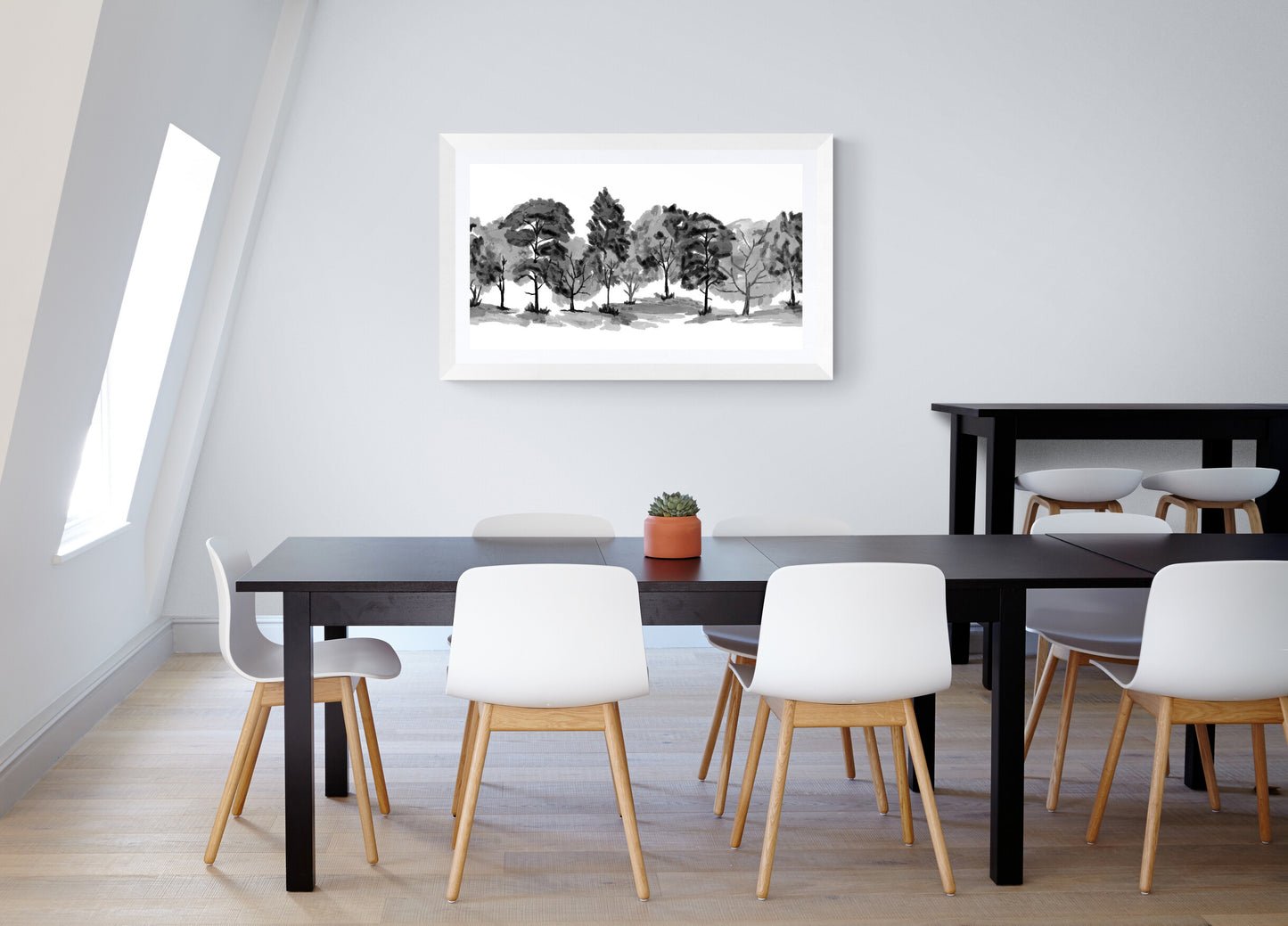 Modern dining room with black table, white chairs, and a framed landscape print on the wall.