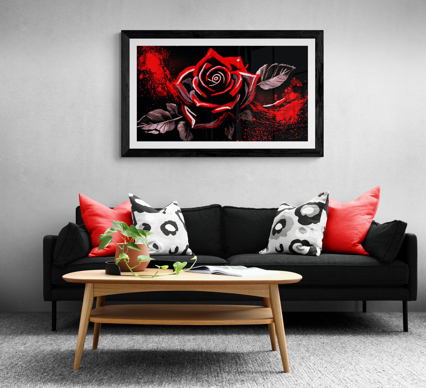 Living room with a black sofa, red and white pillows, and a framed rose art print on the wall.