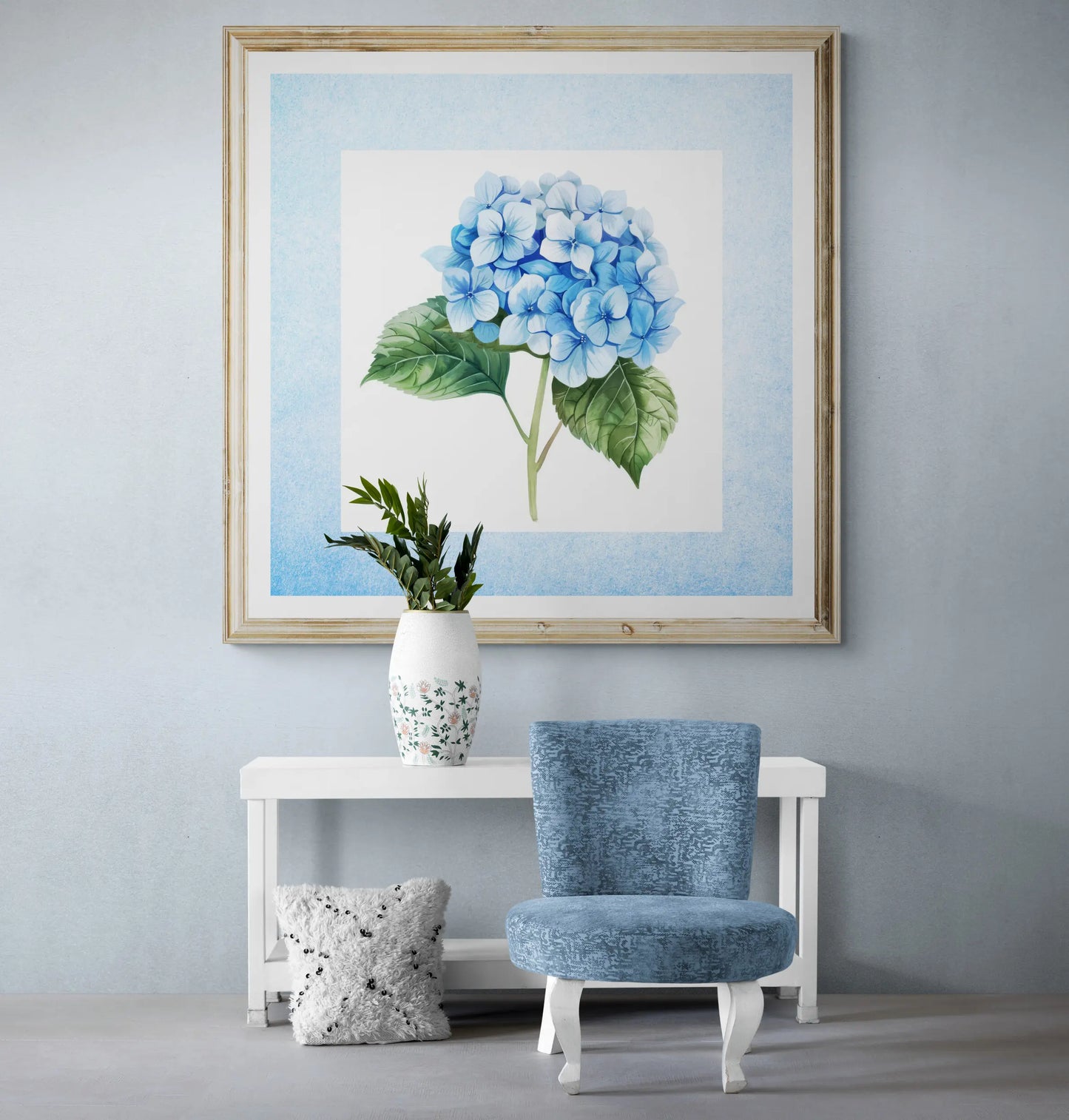 Framed artwork of a blue flower on a wall above a white console table with a blue chair and plant.